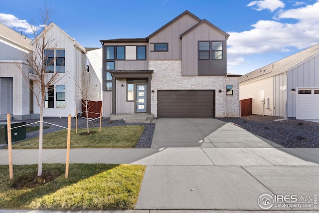 view of front of home featuring board and batten siding, concrete driveway, a garage, and fence