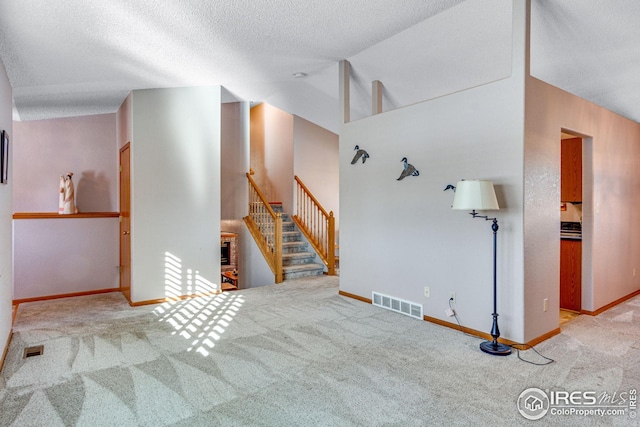 unfurnished living room featuring a textured ceiling, light carpet, and vaulted ceiling