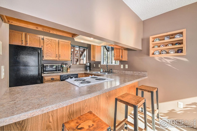 kitchen featuring black appliances, kitchen peninsula, sink, and a kitchen breakfast bar