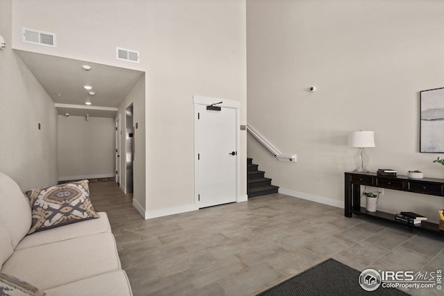 living area featuring visible vents, baseboards, wood finished floors, and stairs