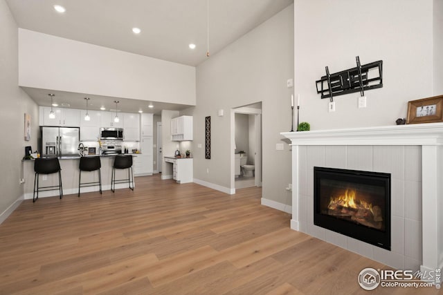 living area with recessed lighting, light wood-style floors, baseboards, and a tile fireplace