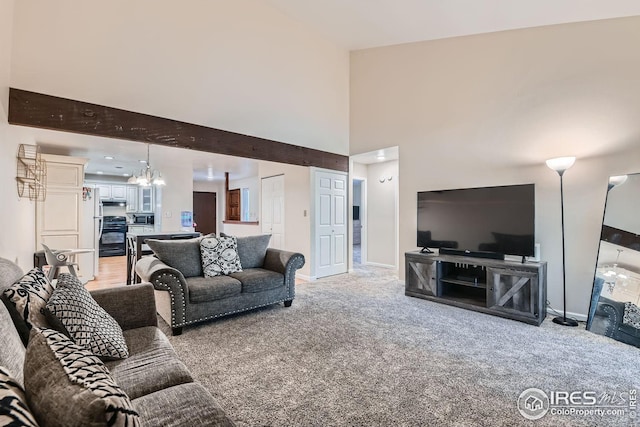 carpeted living room with beamed ceiling and a notable chandelier