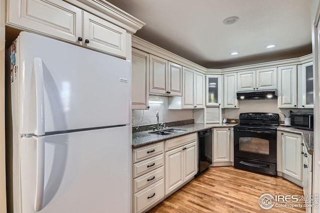 kitchen featuring sink, white cabinets, dark stone counters, light hardwood / wood-style floors, and black appliances