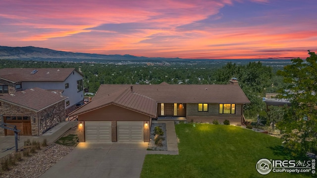 view of front of house featuring a mountain view, a lawn, and a garage