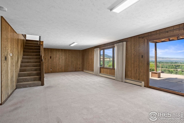 interior space with a textured ceiling, light colored carpet, and wooden walls