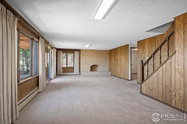 unfurnished living room with a brick fireplace, a baseboard radiator, light carpet, and wood walls