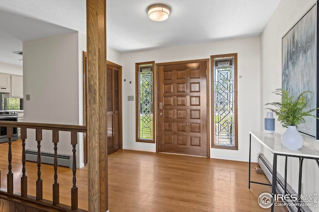 entryway with a healthy amount of sunlight, a baseboard heating unit, and hardwood / wood-style floors