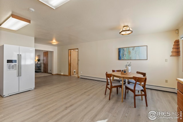 dining space featuring a baseboard radiator and light wood-type flooring