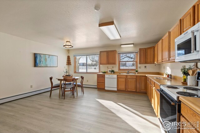 kitchen with light hardwood / wood-style floors, sink, white appliances, and a textured ceiling