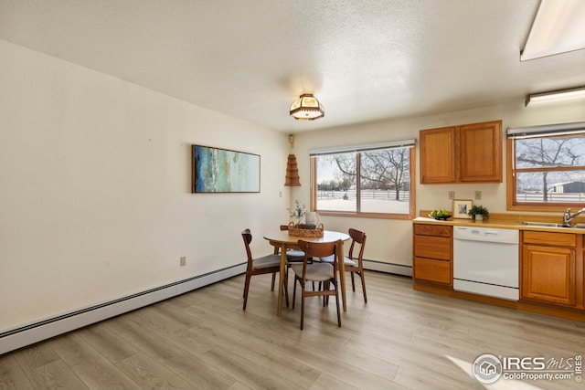 dining room with sink, light hardwood / wood-style flooring, a textured ceiling, and a baseboard heating unit