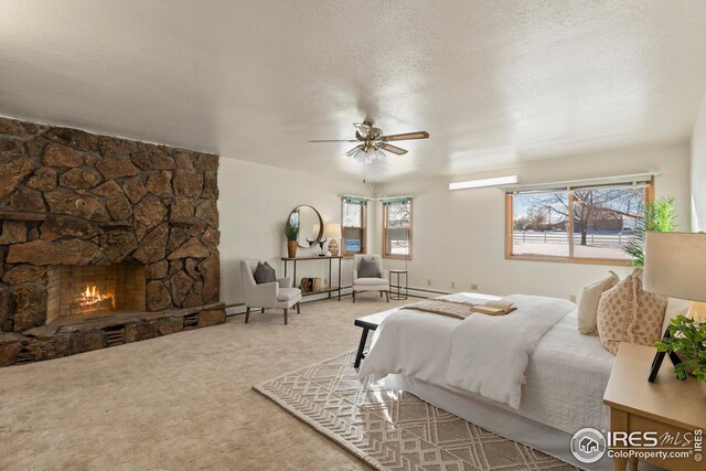carpeted bedroom featuring ceiling fan, a stone fireplace, a textured ceiling, and multiple windows