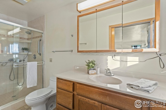 bathroom featuring toilet, a shower with shower door, and vanity