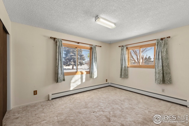carpeted spare room with a baseboard radiator and a textured ceiling