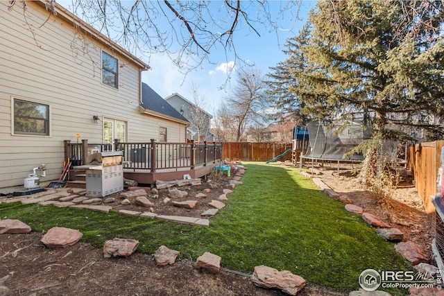 view of yard with a playground, a trampoline, a fenced backyard, and a wooden deck