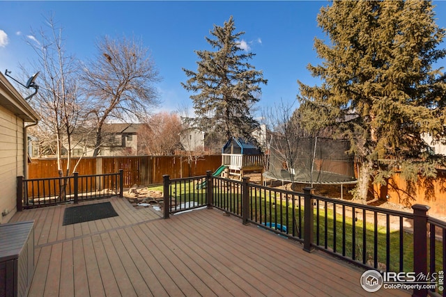 wooden deck with a playground, a trampoline, a fenced backyard, and a yard