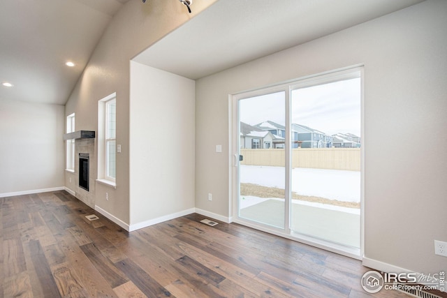 unfurnished living room featuring a tiled fireplace, dark wood-type flooring, and baseboards