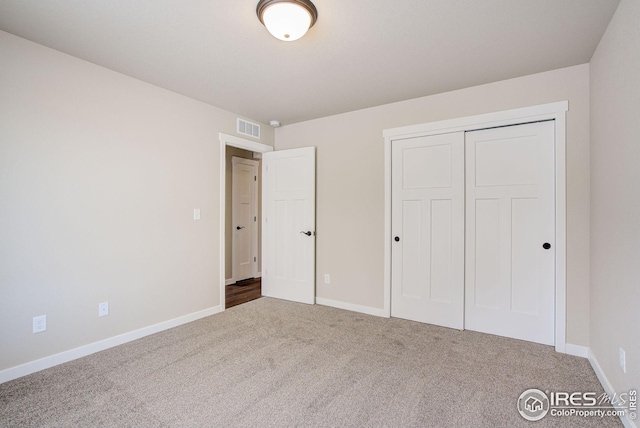 unfurnished bedroom featuring carpet flooring, baseboards, visible vents, and a closet