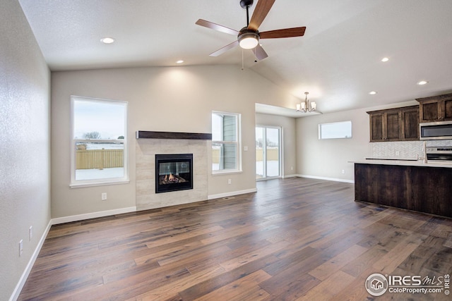 kitchen with dark wood-type flooring, dark brown cabinets, appliances with stainless steel finishes, a tiled fireplace, and open floor plan