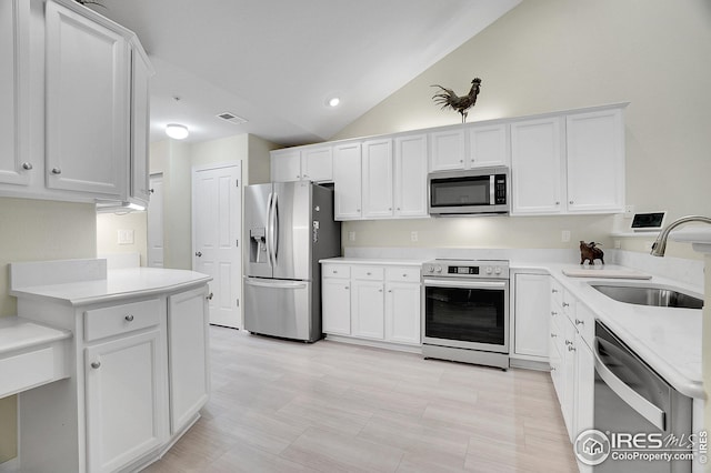 kitchen featuring sink, vaulted ceiling, white cabinets, and appliances with stainless steel finishes