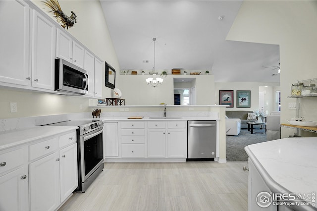 kitchen featuring sink, white cabinetry, hanging light fixtures, stainless steel appliances, and light stone countertops