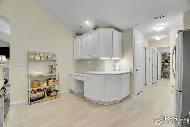 kitchen featuring stainless steel refrigerator, white cabinetry, and vaulted ceiling