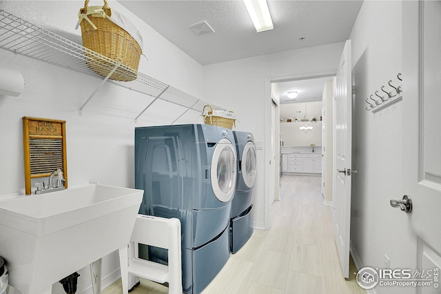 laundry area featuring separate washer and dryer, sink, and a textured ceiling