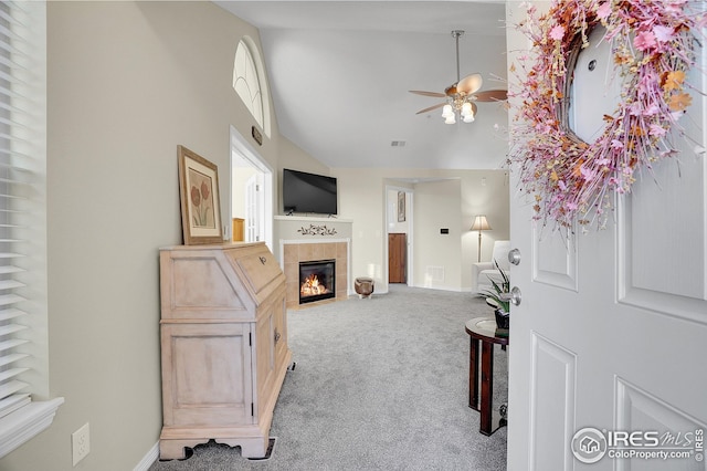 living room with a high ceiling, a tile fireplace, light carpet, and ceiling fan