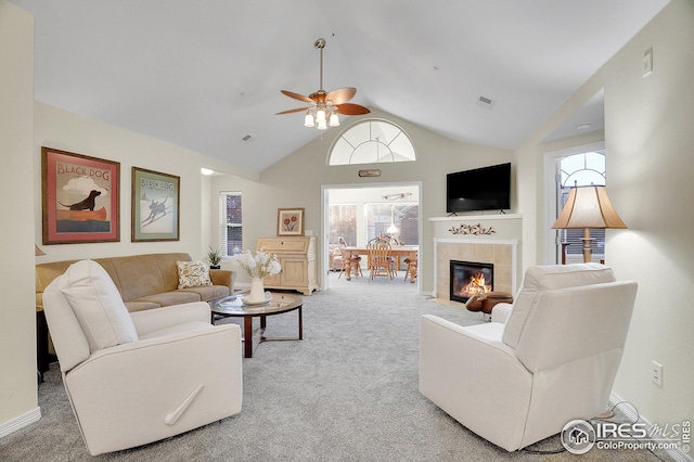 living room with ceiling fan, carpet flooring, a tiled fireplace, and high vaulted ceiling