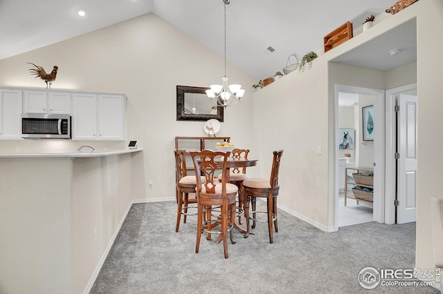 carpeted dining room featuring high vaulted ceiling and a chandelier