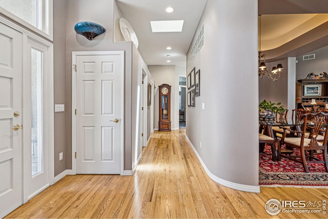 hallway featuring light wood-type flooring and an inviting chandelier