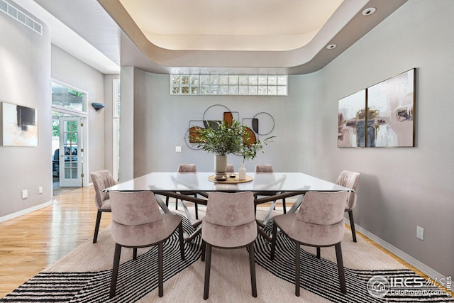 dining room featuring a tray ceiling and light wood-type flooring