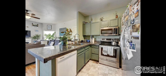 kitchen with sink, green cabinets, kitchen peninsula, and appliances with stainless steel finishes