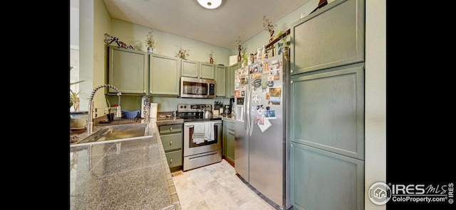 kitchen with sink, green cabinets, and appliances with stainless steel finishes