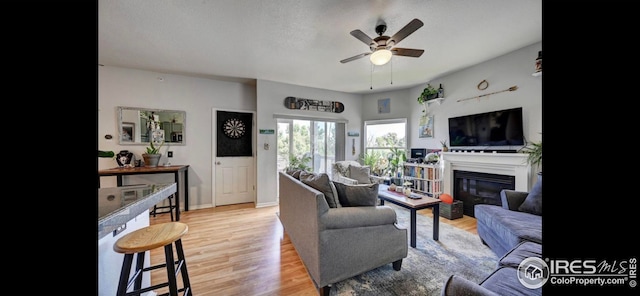 living room with a textured ceiling, light hardwood / wood-style flooring, and ceiling fan