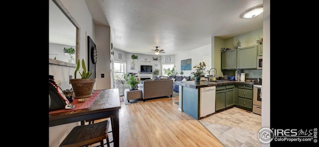 kitchen with stainless steel electric stove, green cabinetry, sink, white dishwasher, and kitchen peninsula