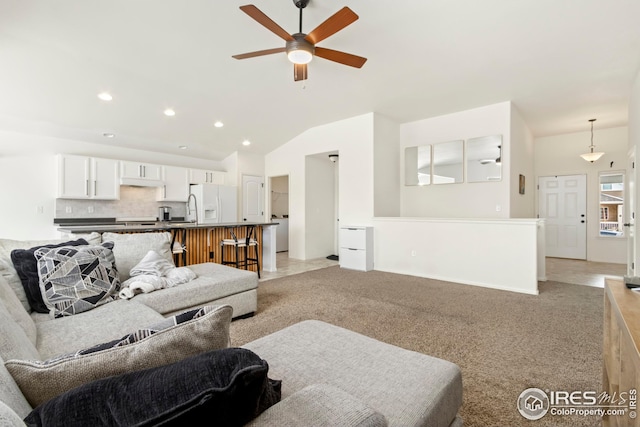 living room with vaulted ceiling, ceiling fan, and light colored carpet