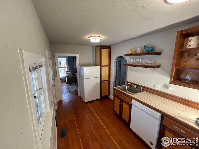 kitchen with sink, white appliances, tile countertops, and dark wood-type flooring