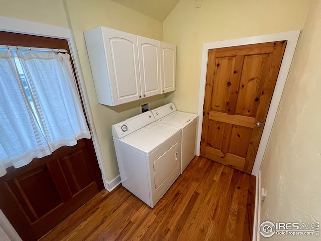 clothes washing area featuring dark wood-type flooring, cabinets, and washing machine and clothes dryer