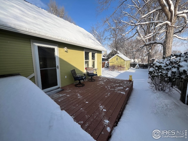 snow covered deck featuring a storage shed