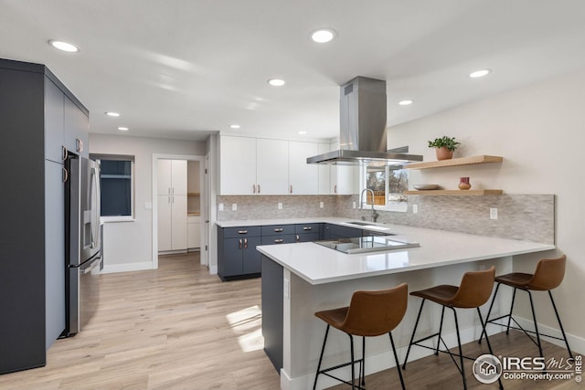 kitchen with island range hood, a breakfast bar area, and kitchen peninsula