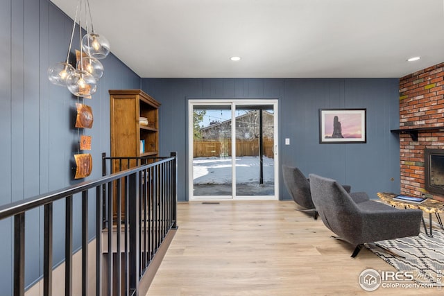 living room with a brick fireplace and light hardwood / wood-style flooring