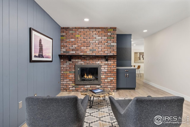 living room featuring a brick fireplace and light wood-type flooring