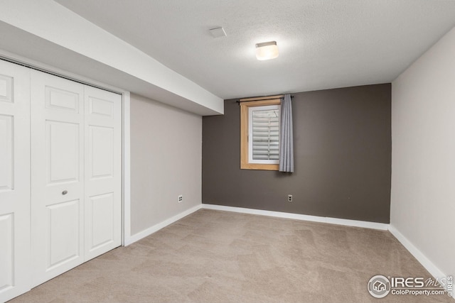 basement featuring light colored carpet and a textured ceiling