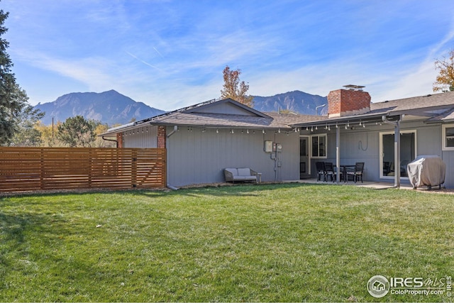 back of house with a patio, a mountain view, and a lawn