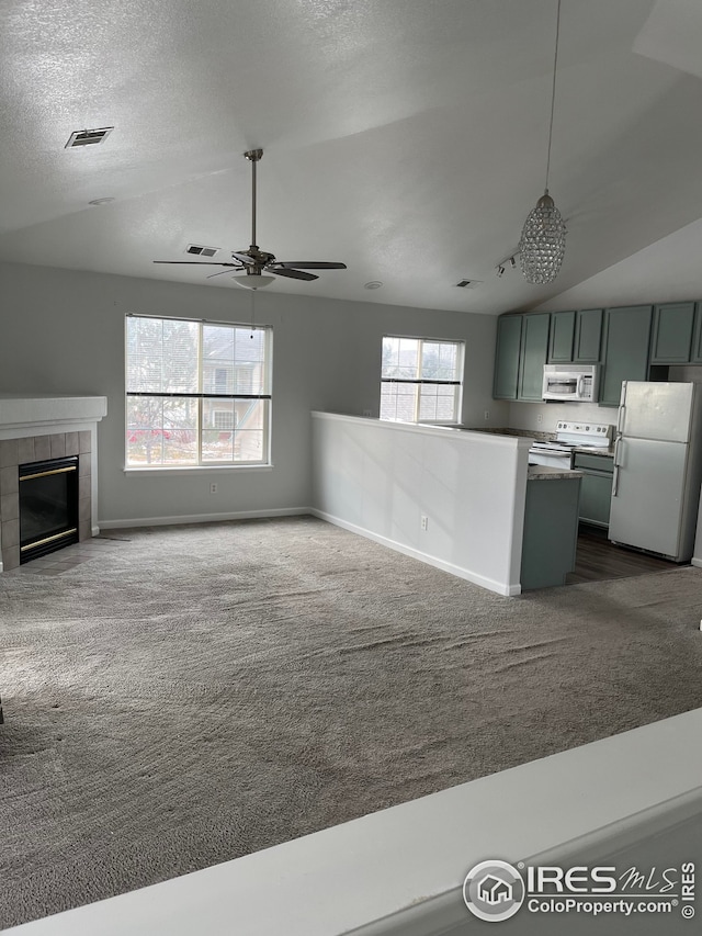 unfurnished living room featuring lofted ceiling, dark colored carpet, a textured ceiling, ceiling fan, and a fireplace