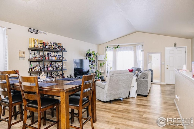 dining room with lofted ceiling, a textured ceiling, and light hardwood / wood-style floors