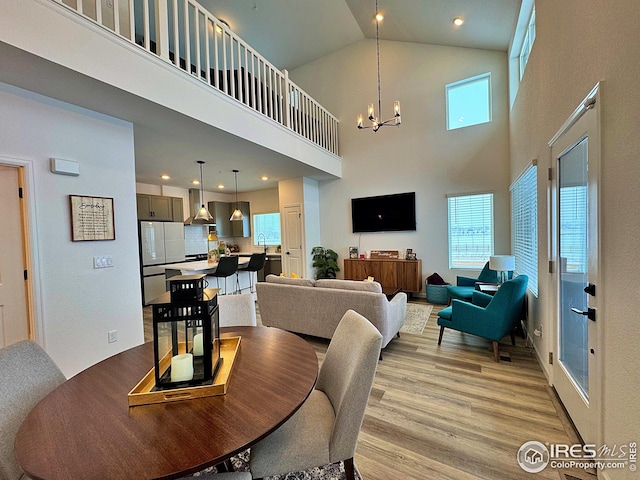 dining room with a towering ceiling, a chandelier, and light hardwood / wood-style flooring