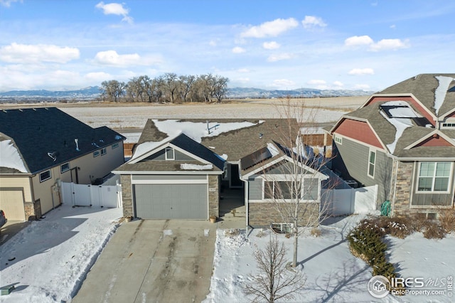 view of front of house featuring concrete driveway, an attached garage, a mountain view, a residential view, and stone siding