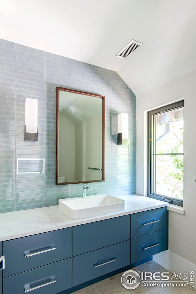 3621 21st St, Boulder, CO 80304 - bathroom featuring tile walls, vanity, lofted ceiling, decorative backsplash, and baseboards
