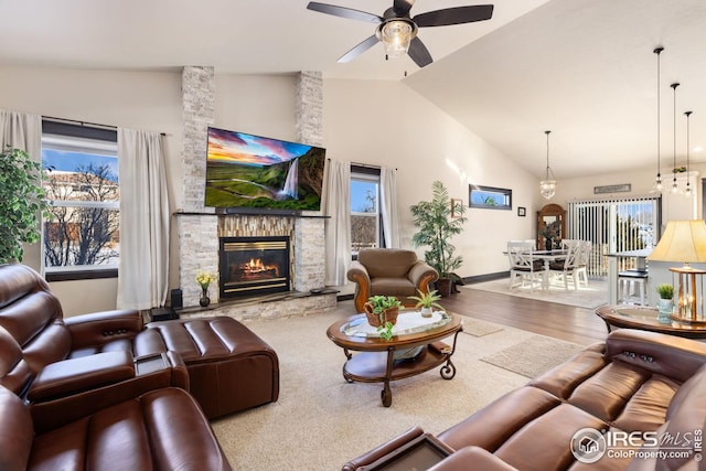 living room featuring wood-type flooring, lofted ceiling, a wealth of natural light, and a stone fireplace